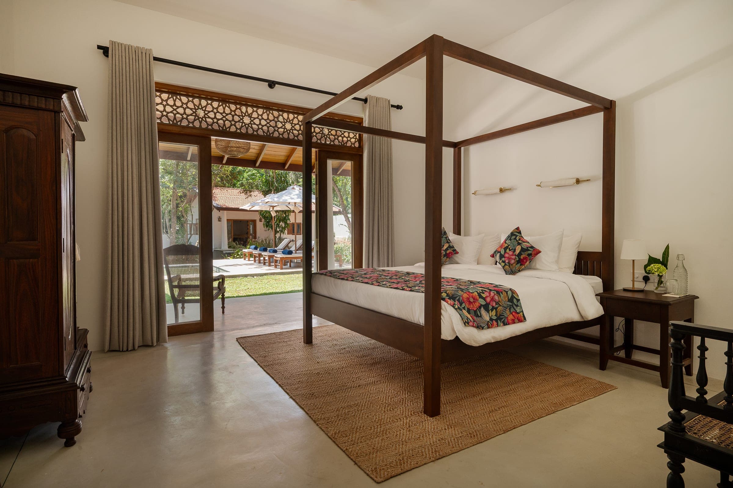 Bedroom One at Kottamba Kanda: a four-poster bed, an antique wardrobe and double doors open to the verandah and pool
