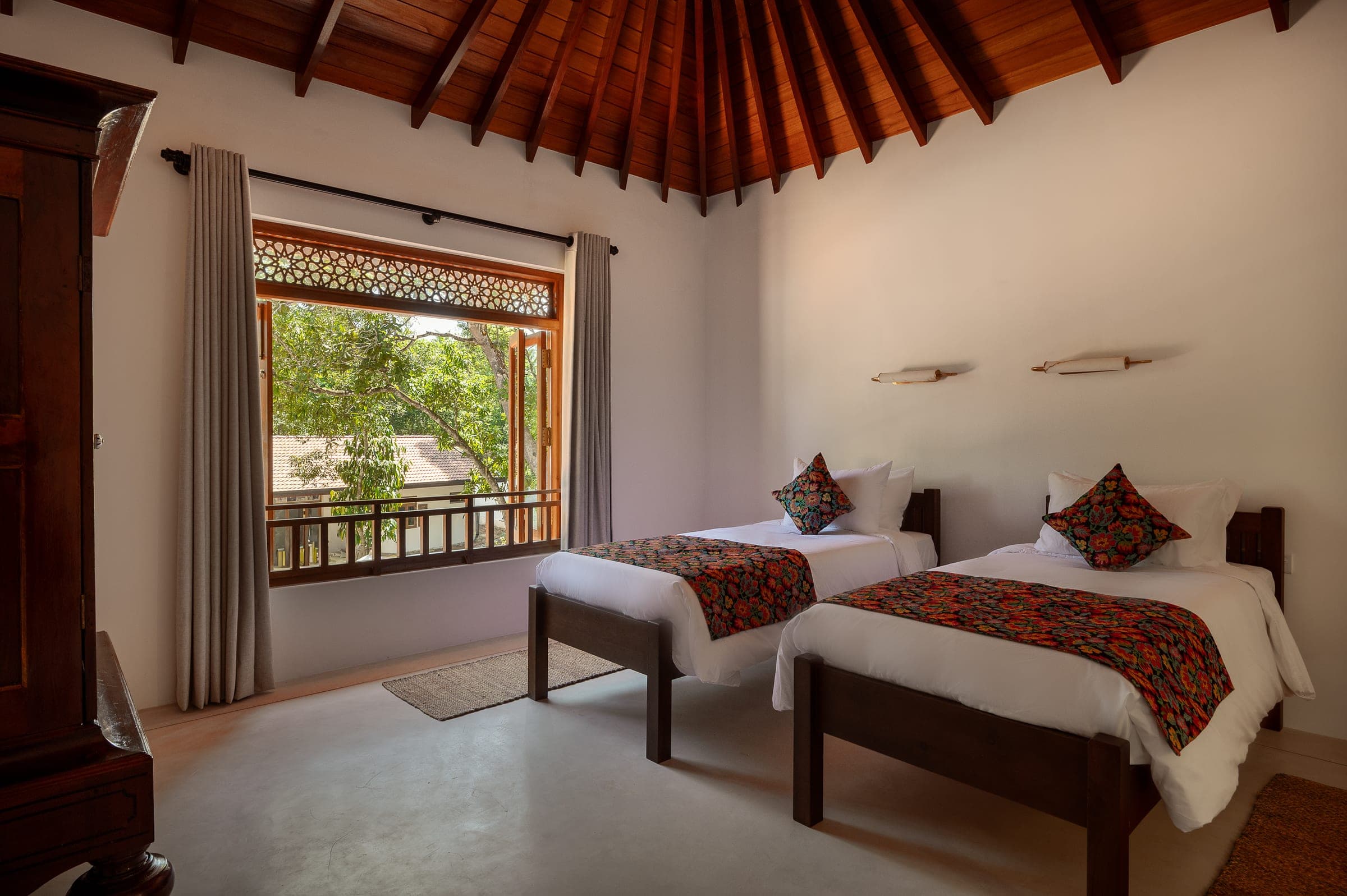 Bedroom Three on the first floor, made up as a twin, under the vaulted timber ceiling with a window onto the trees