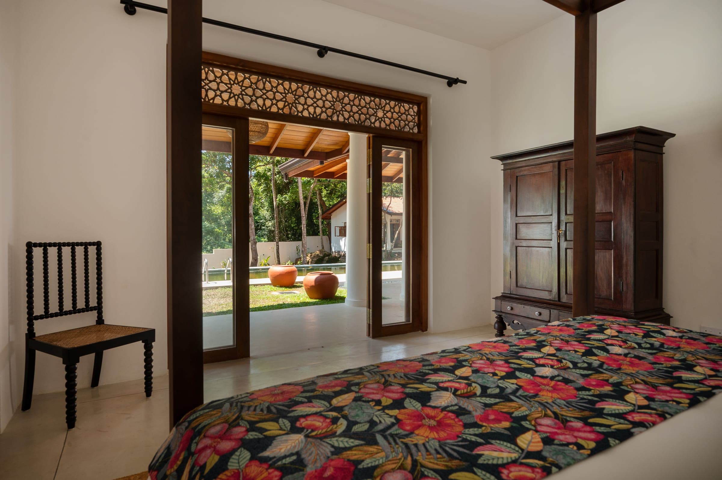 Bedroom Two's double doors open to the garden and verandah, an antique wardrobe beside the bed