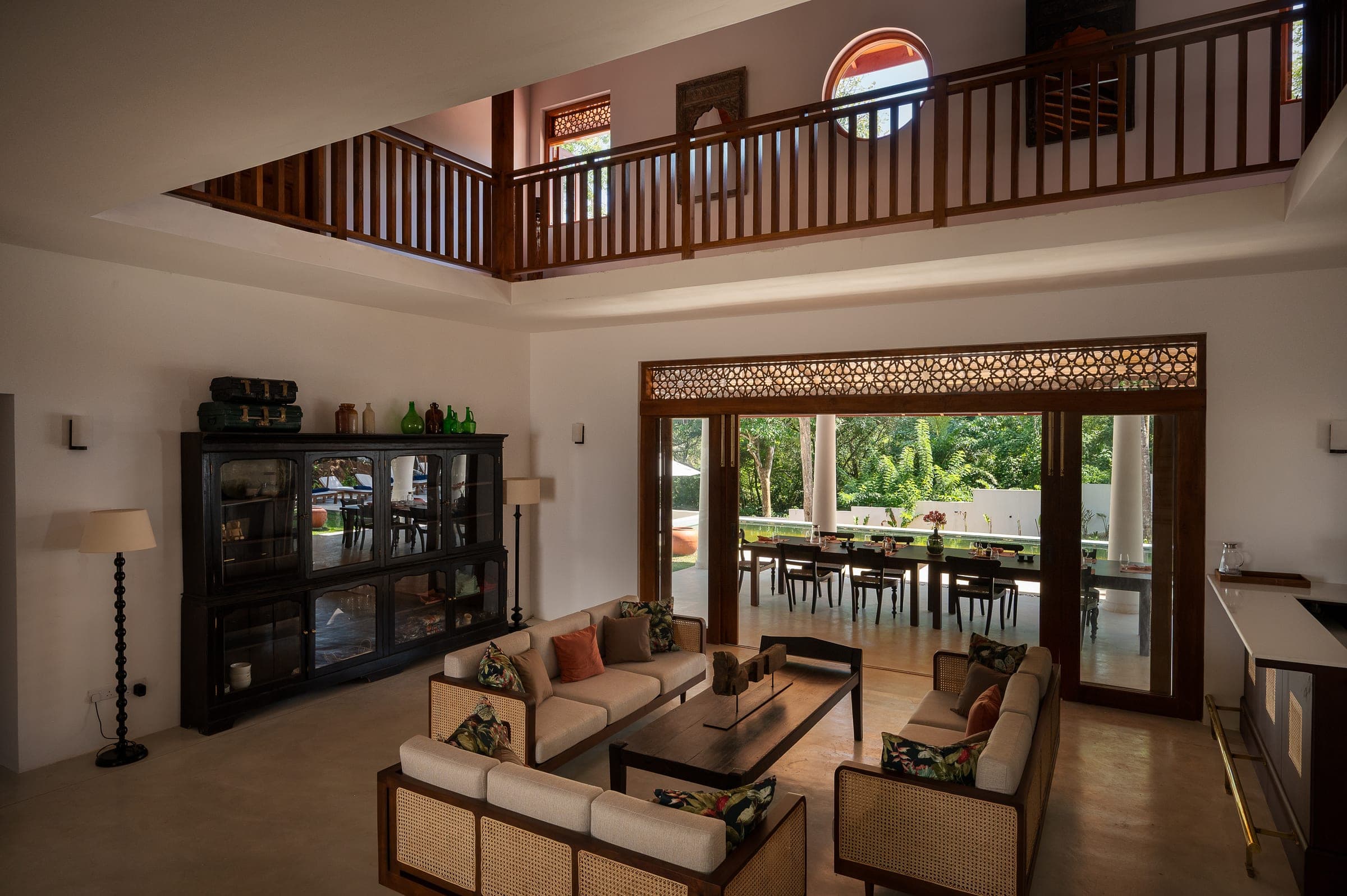 The living room at Kottamba Kanda: cane sofas under the first-floor gallery, doors open to the dining verandah and pool