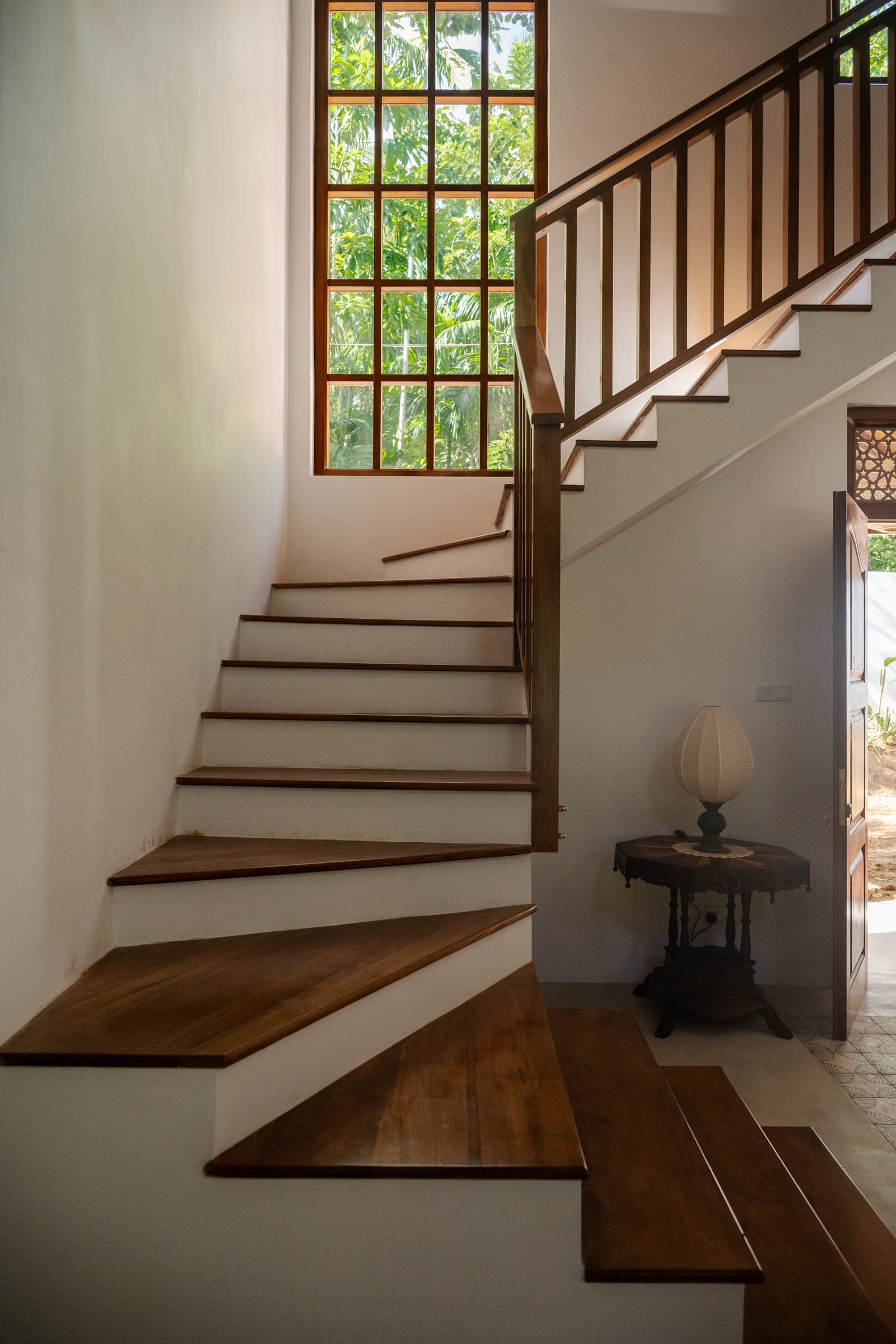 The teak staircase in the main villa, lit by a tall window onto the garden