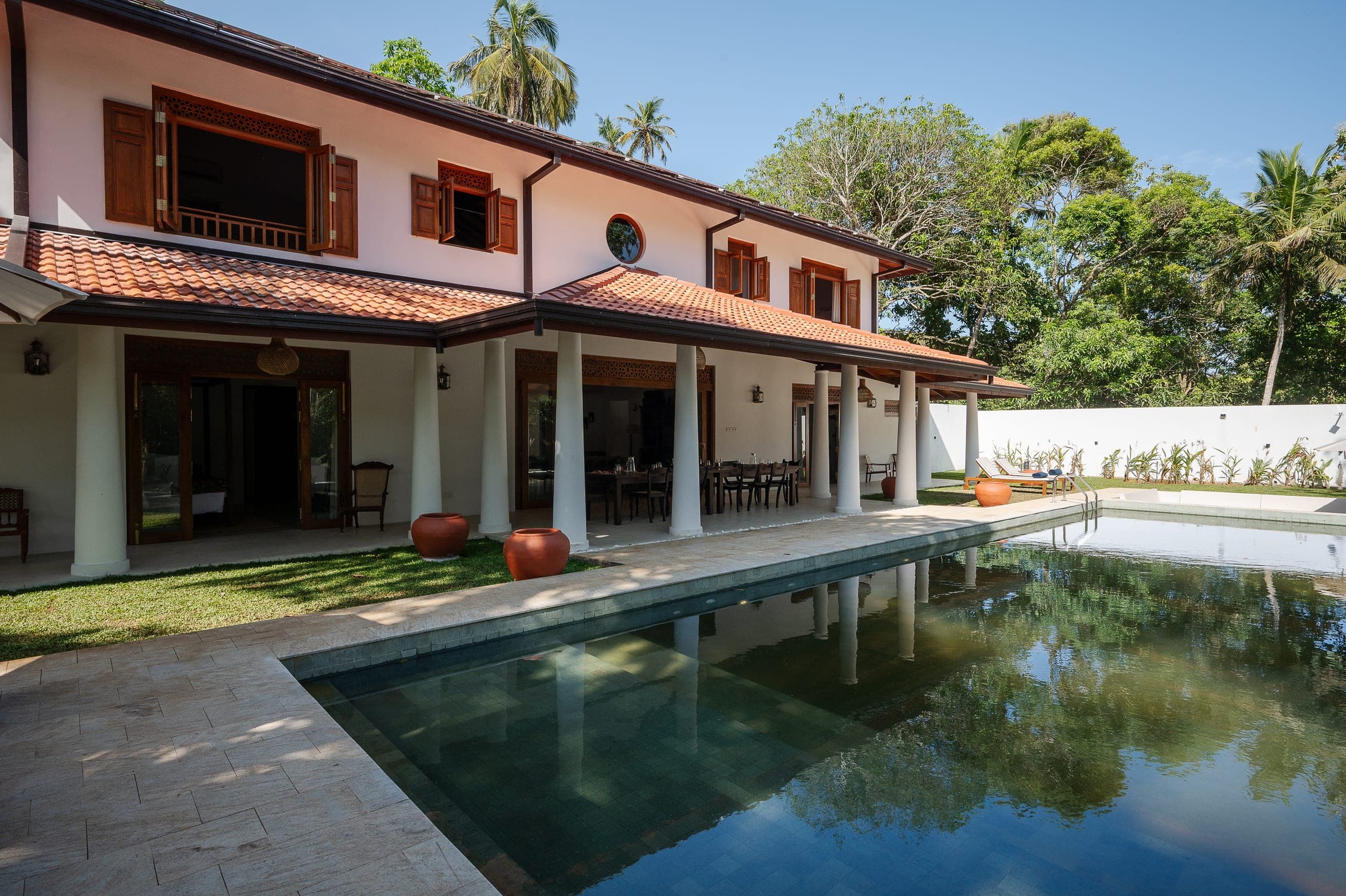 Kottamba Kanda, a six-bedroom private villa near Hiriketiya, Sri Lanka: the white house and its columned verandah beside the green-tiled pool